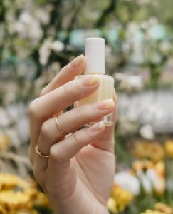 close-up of a woman's hands holding a yellow nail polish bottle
