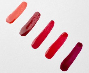 swatches of red and orange nail polish shades on paper