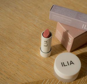 Ilia makeup products on wood table