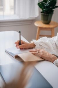 Close-up of a woman writing in a journal.