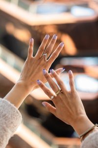 woman's hands in front of The Vessel in NYC, with simple blue and purple nail art