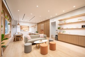 sundays studio hudson yards nail salon; bright nail salon with sofa, coffee table, manicure tables and chairs and a long credenza with floating shelves along the wall
