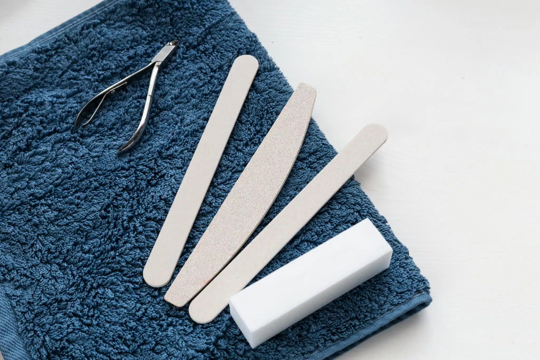 nail filing and trimming tools on a dark blue towel