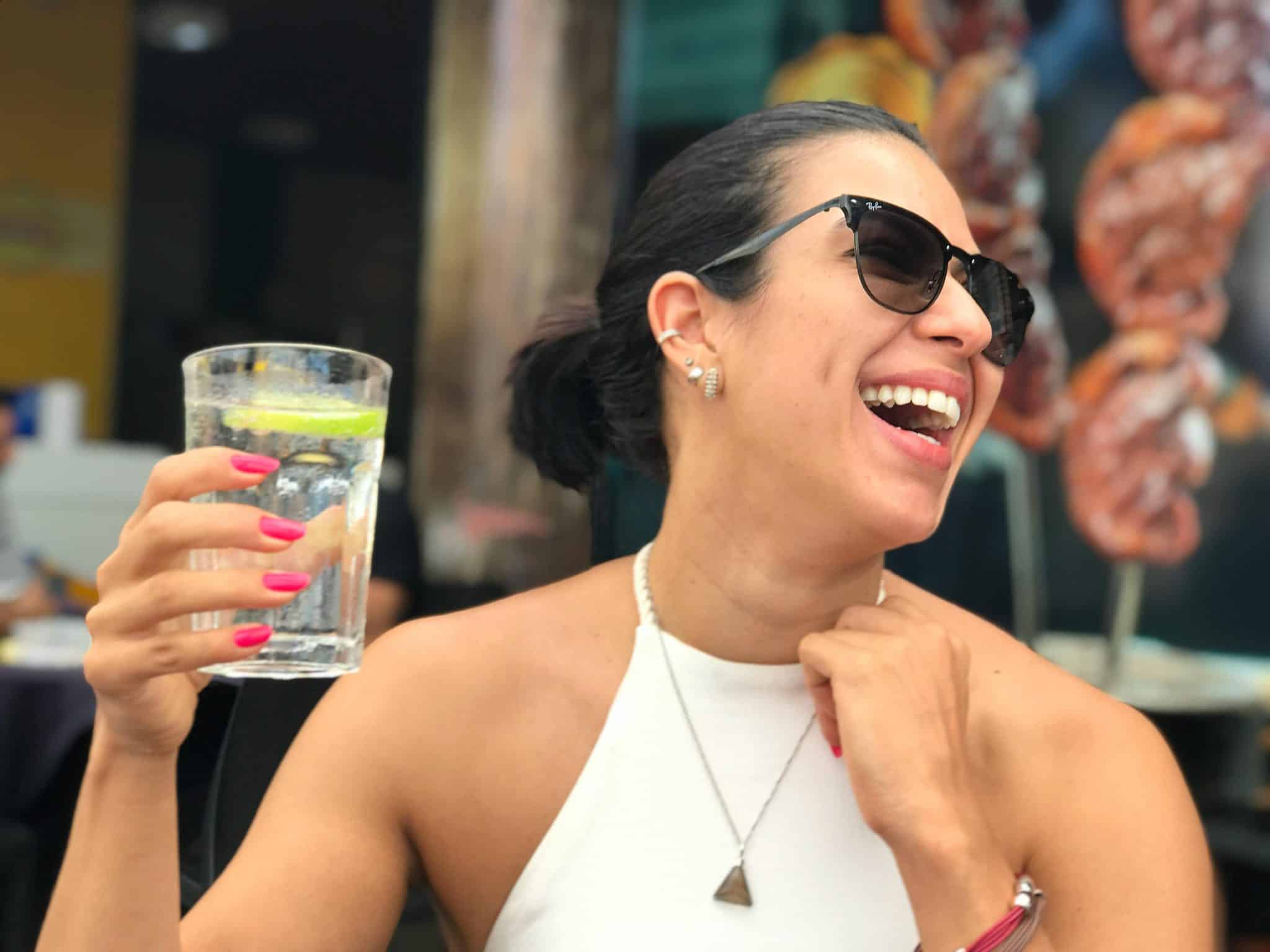 woman smiling and holding drink with pink nails