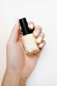 woman with yellow nail polish on fingernails holding a bottle of yellow nail polish