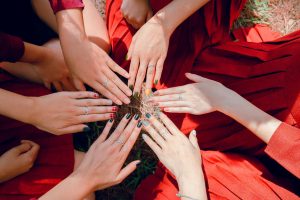 Women showing their hands with bright nail colors and red dresses