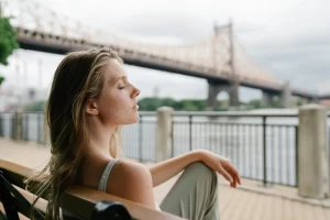 woman sitting on bench and looking at bridge