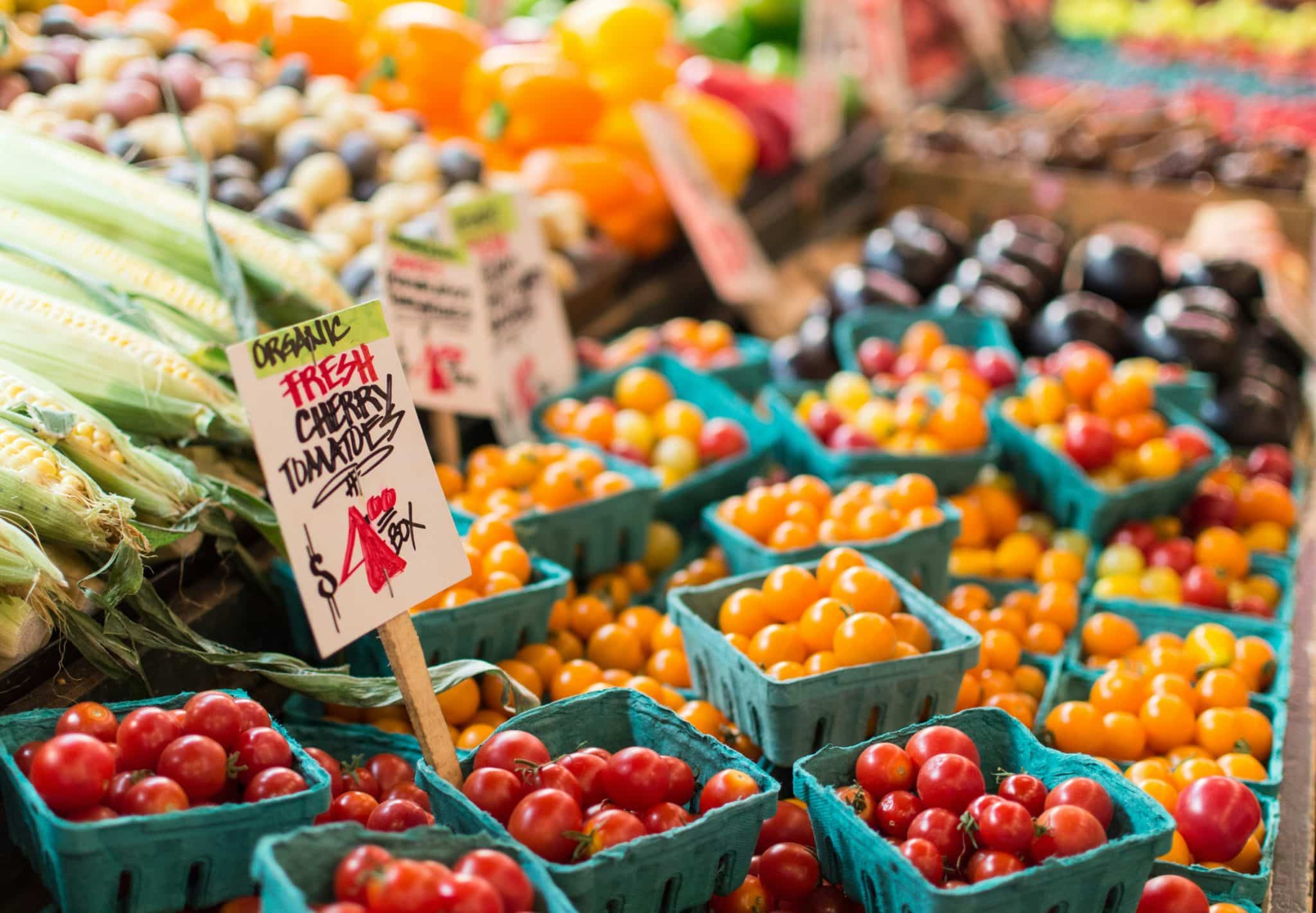 Farm stand with a variety of organic cherry tomatoes, corn, and other vegetables