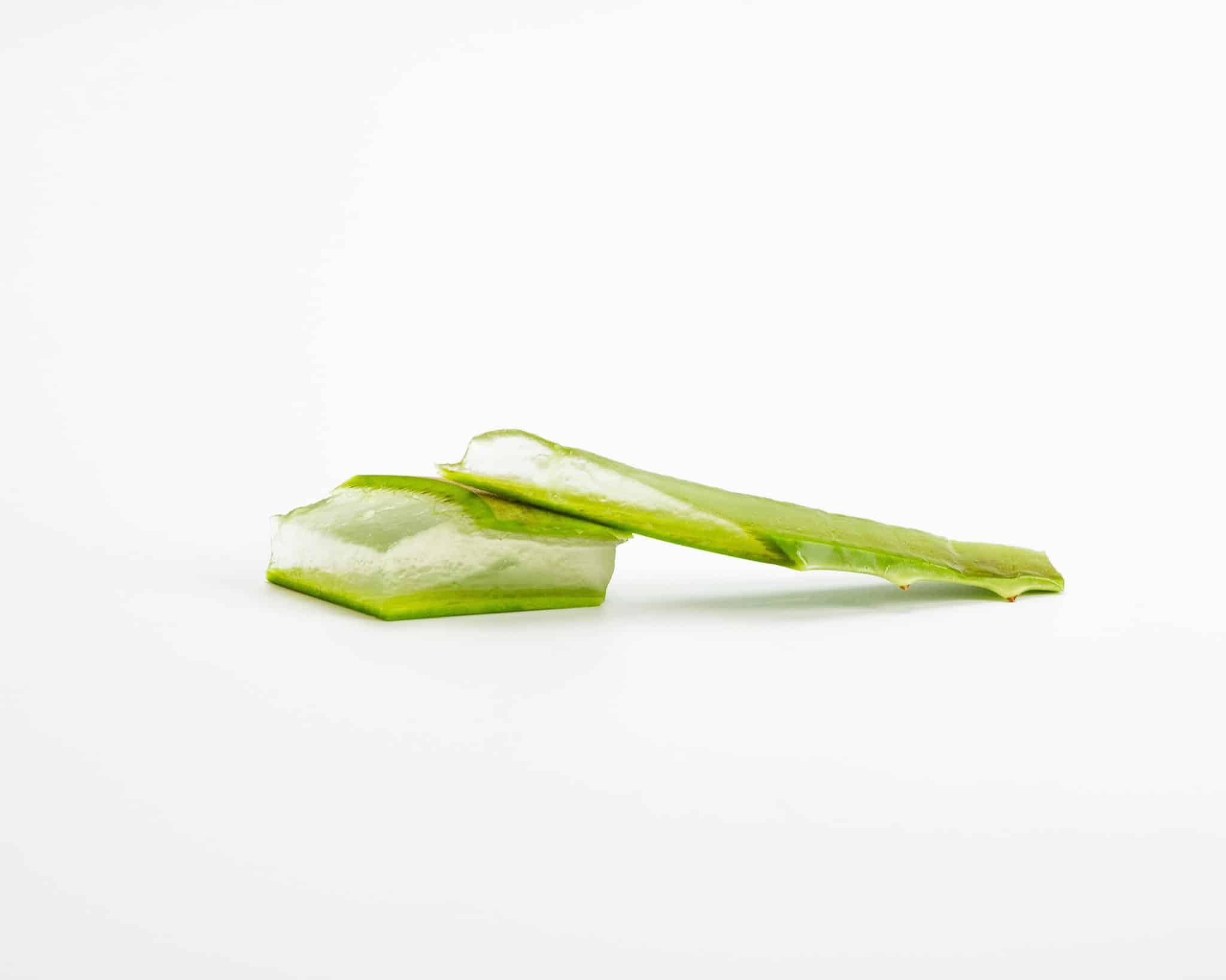 two pieces of aloe vera with the flesh exposed, sitting against a white background