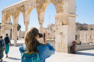 Woman taking a photo with a digital camera at a historical site.