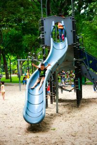 A child riding down a blue slide at a playground.