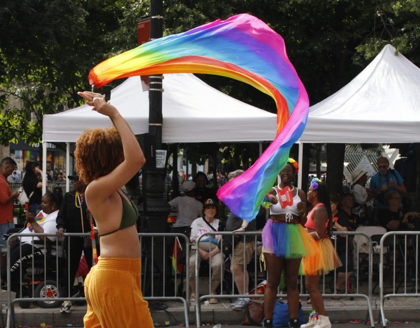 Woman waving pride flag at a pride march outside in Central Park.