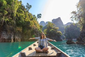 Woman sitting on a boat on a river in a tropical, mountainous location.