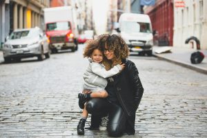 Mother holding daughter on cobble street.