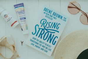 a books, mineral sunscreen products, sunglasses and other beach essentials on a table