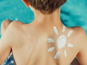 sun painted in sunscreen on a boy's back