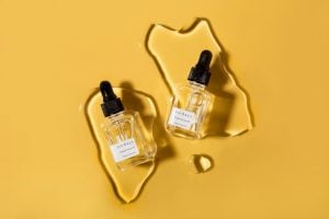 two bottles of cuticle serum in front of yellow background