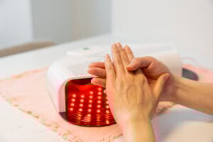 Woman holding her hands in front of red light therapy hand mask