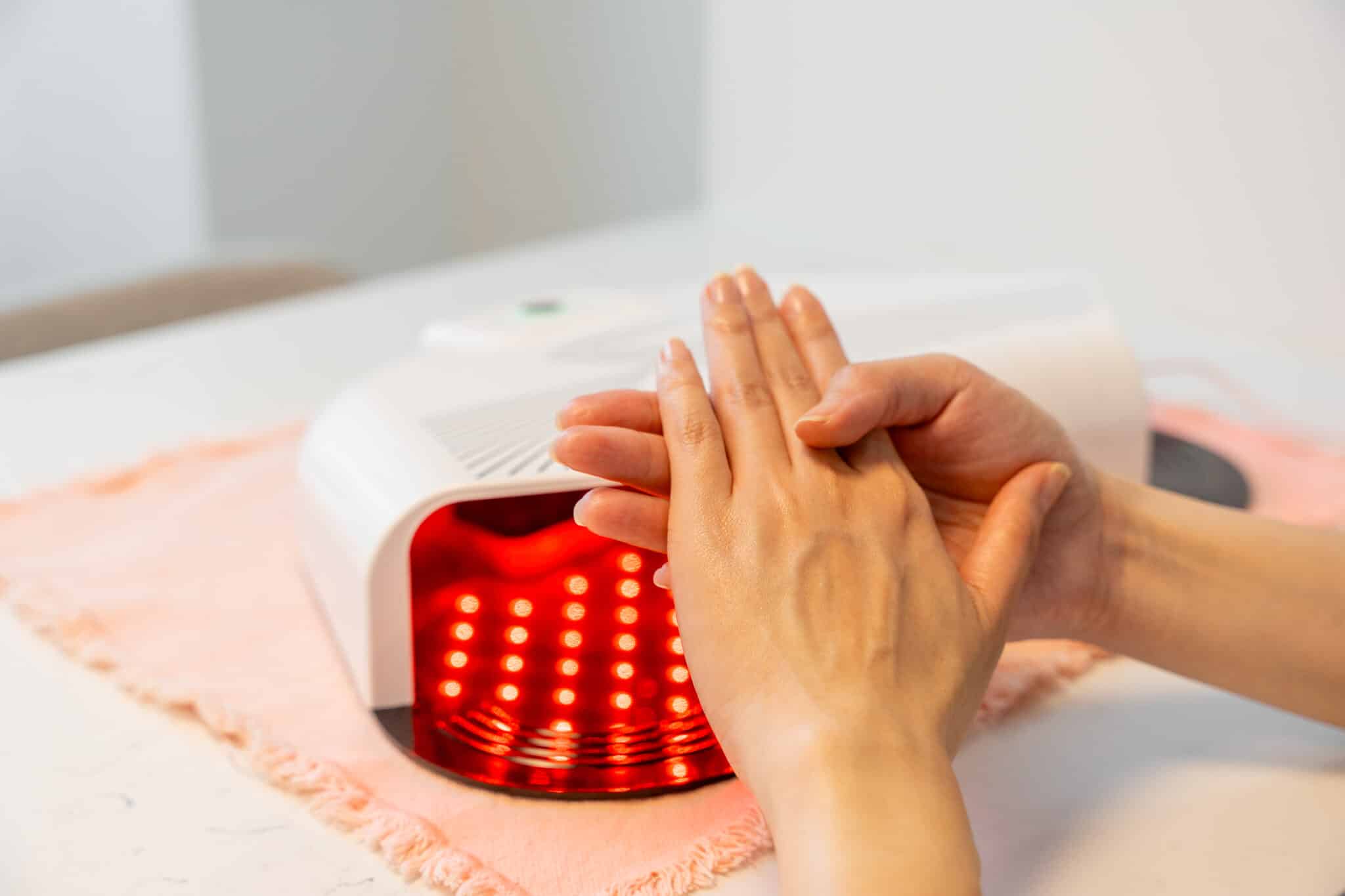 Woman holding her hands in front of red light therapy hand mask